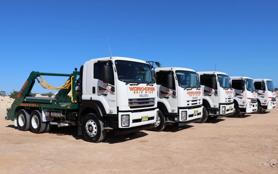 Fleet of Workhorse trucks lined up on a construction site, ready for skip bin booking.