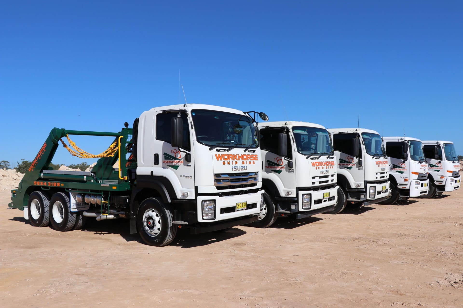 Fleet of Workhorse trucks lined up on a construction site, ready for skip bin booking.